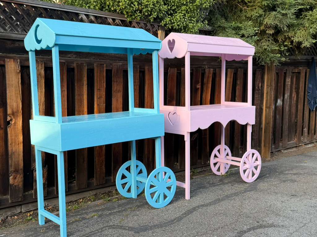 Pair of handmade wooden vendor carts in pastel pink and light blue with wagon wheels