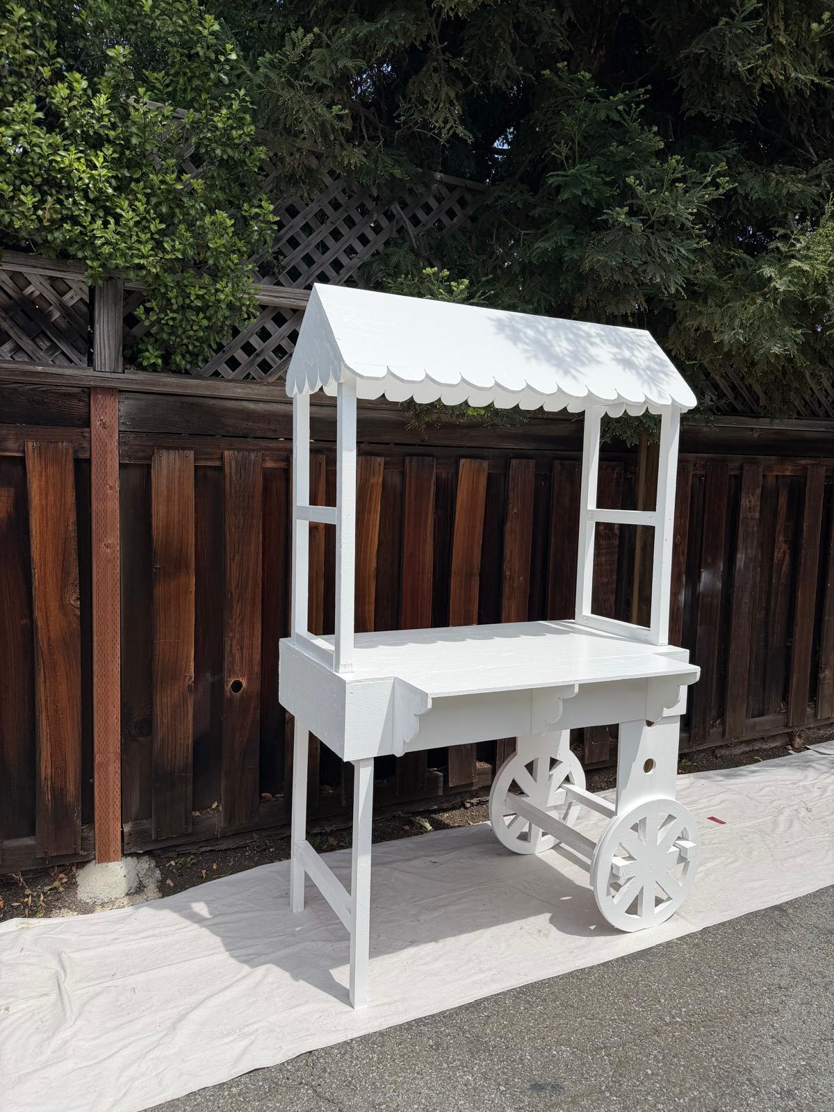 Handmade wooden vendor cart with scalloped roof and wagon wheels