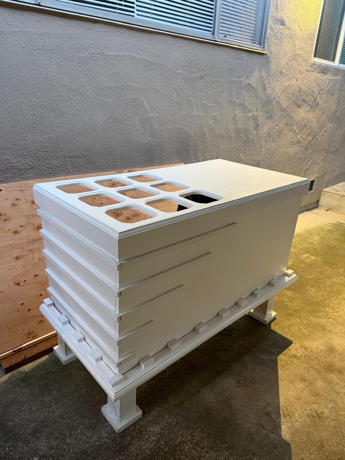 Honeycomb display table with nine cellular compartments on a slatted pedestal